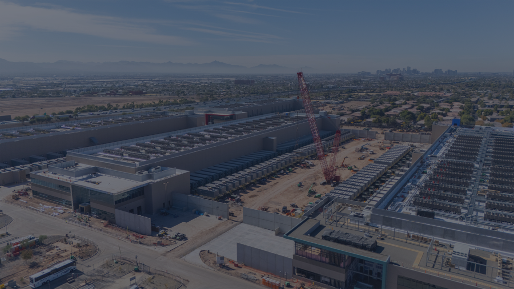 An aerial view of a sprawling rural data center construction site with perimeter fencing, truck gates, and distributed work zones across open terrain, illustrating why data center builds need build-specific Predictive Safety Management.